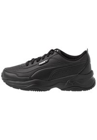 Scarpa da ginnastica nera con tomaia in pelle, accenti testurizzati, colletto imbottito e suola in gomma spessa. Presenta fori lungo il lato e un logo.