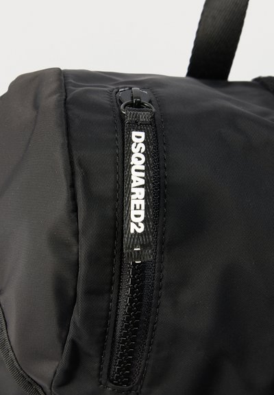 Μαύρη υφασμάτινη τσάντα με κάθετο φερμουάρ που διαθέτει ταινία έλξης με την επιγραφή "DSQUARED2" σε λευκά γράμματα.