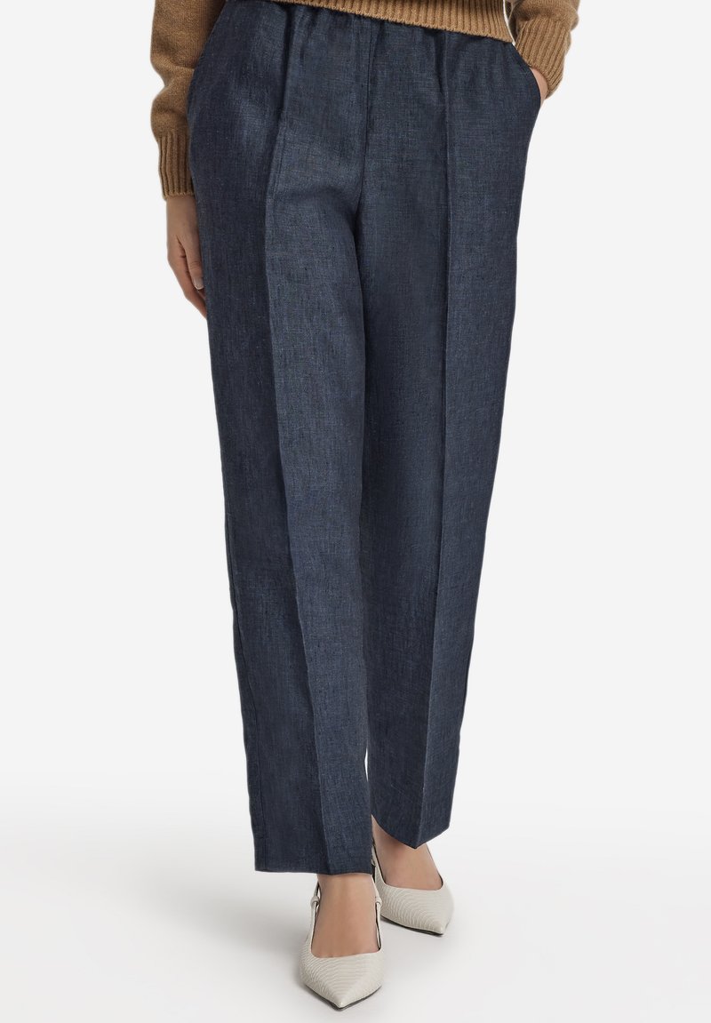 Mörkblå byxor i linneblandning med pressveck och avslappnad passform, med hög midja och sidofickor, kombinerade med vita spetsiga skor.
