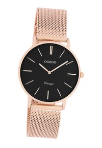 Cadran de montre noir rond avec des accents en or rose, doté d'un bracelet en maille. Design minimaliste avec des marques horaires et le texte 'Vintage'.