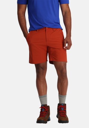 Rode shorts van lichtgewicht stof met een gladde textuur. Gepaard met bruine wandelschoenen met rode veters en grijze crew-sokken.