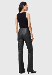 Black sleeveless top with a fitted design paired with high-waisted black leather pants, featuring a smooth texture and flared leg silhouette.
