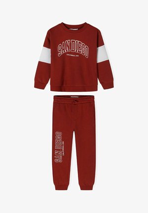 Ensemble sweat-shirt et pantalon rouge avec des rayures blanches. Présente le texte "SAN DIEGO" en blanc. Tissu doux, poignets et taille côtelés.
