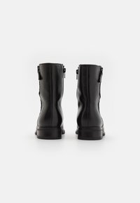 Černé kožené kotníkové boty s hladkým povrchem, zaoblenou špičkou a nízkým lepeným podpatkem. Obsahují zipy po obou stranách pro snadné obouvání.