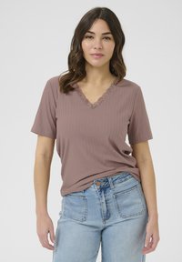 Camiseta de canalé en rosa empolvado con escote en V adornado con encaje, de manga corta, combinada con jeans de tiro alto en azul claro.