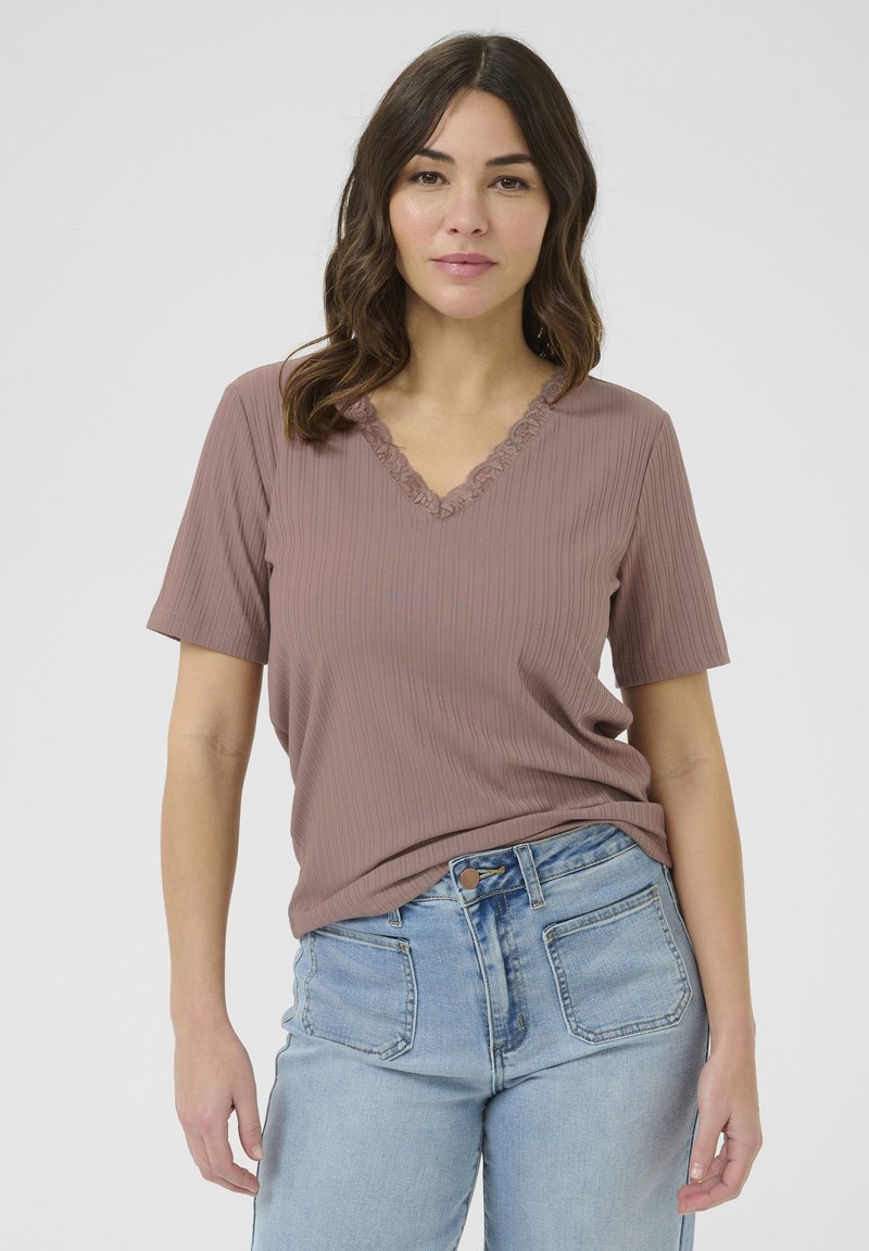 T-shirt côtelé rose poussiéreux avec un col en V orné de dentelle, manches courtes, associé à un jean taille haute bleu clair.