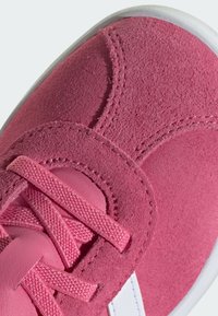 Zapatillas de ante rosa con parte superior texturizada, cordones planos y acentos blancos. Punta redondeada y cuello acolchado para mayor comodidad. Suela de goma.