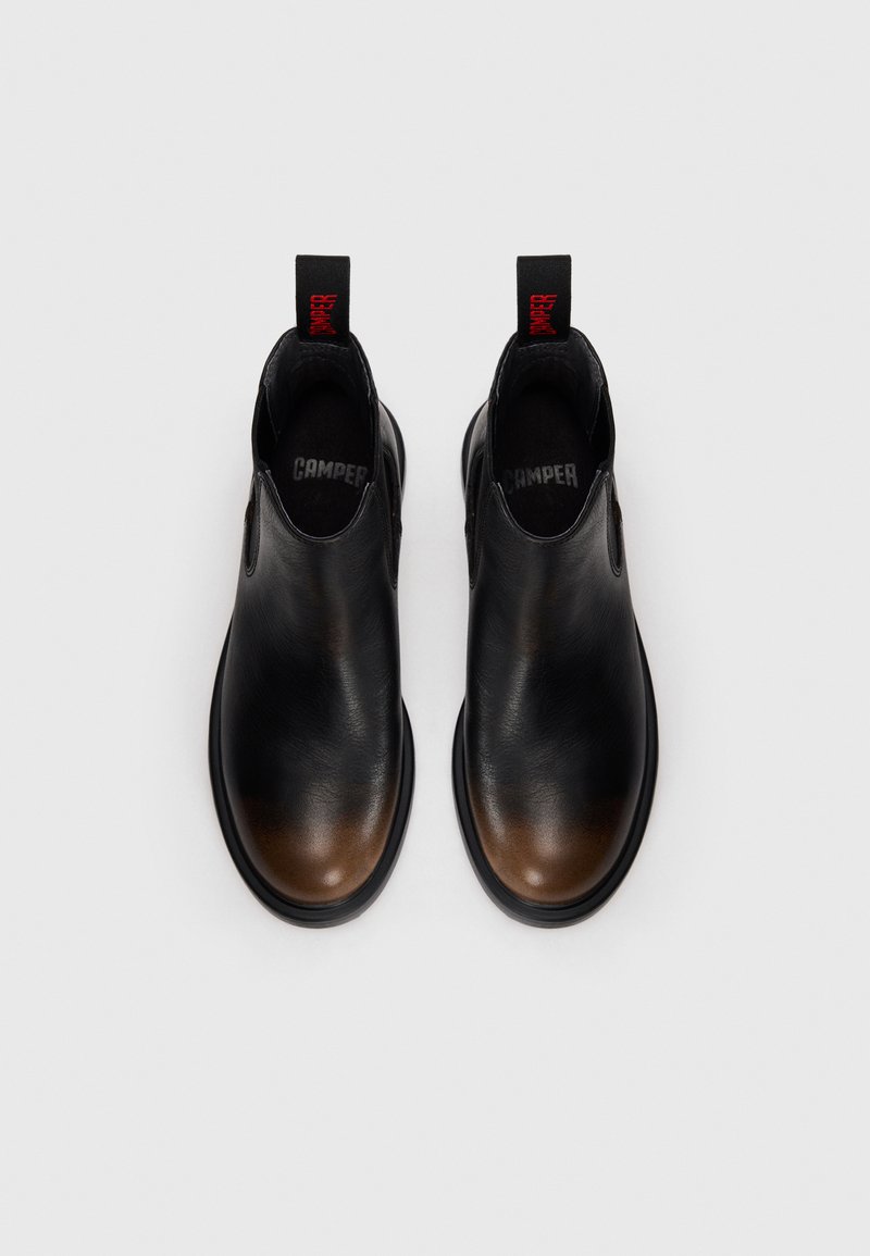 Pair of black leather Chelsea boots with brown toes, black soles, and red pull tabs labeled "DAMPER" facing upwards on white background.