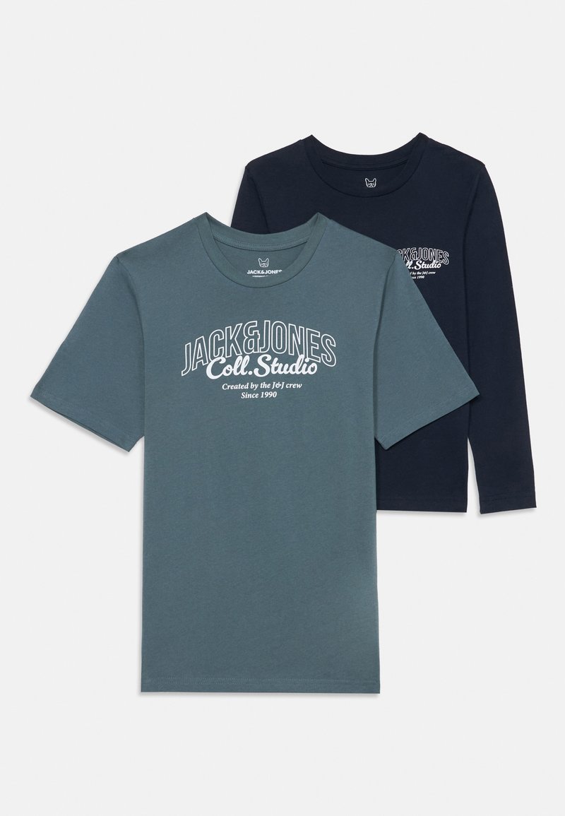 Δύο Τ-σιέρτ: το ένα σε τυρκουάζ, κοντομάνικο με λευκό λογότυπο, και το άλλο σε ναυτικό μπλε, μακρομάνικο με ένα μικρό λευκό λογότυπο στο στήθος.