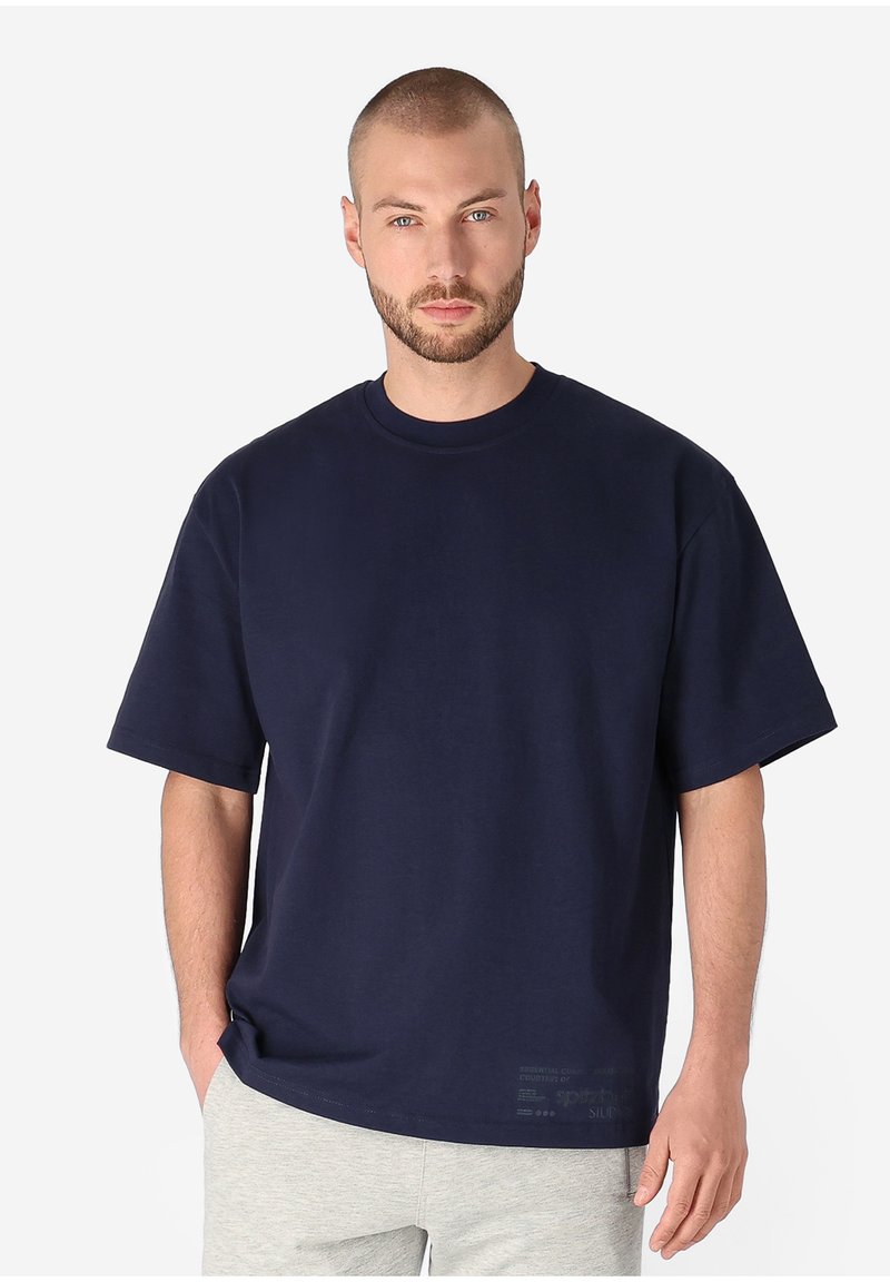 Navy cotton t-shirt with a round neck, short sleeves, and a relaxed fit. Features subtle text detail at the hem. Smooth texture.