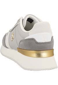 Sneaker grigio con una combinazione di materiali in pelle e camoscio, con dettaglio dorato sul tallone, colletto imbottito e dettagli in tessuto testurizzato.