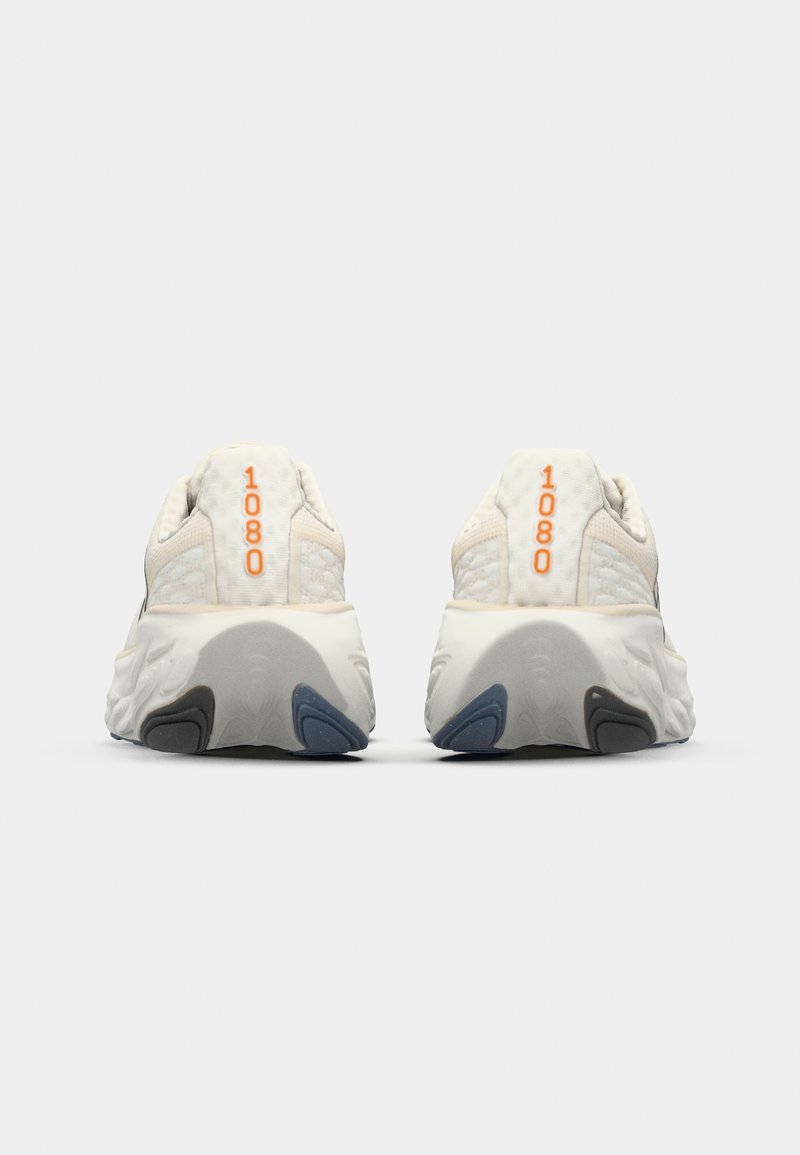 Des chaussures de course de couleur neutre avec un dessus texturé, dotées d'un talon prononcé, d'une semelle en mousse et d'un détail orange "1080" à l'arrière.