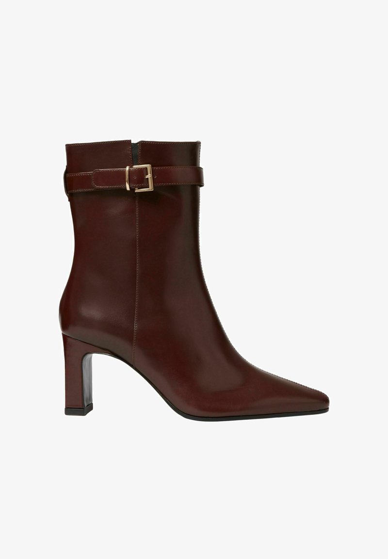 Botín de cuero marrón oscuro con punta afilada, tacón cuadrado y cinta decorativa con hebilla dorada en la parte superior.