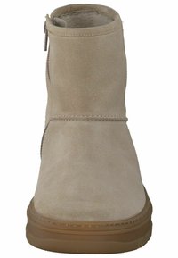 Beige ruskind ankelstøvle med rund tå, lynlås i siden og gummisål. Har blødt foer og syninger langs sømmene.