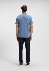 Ljust blå polo skjorta med korta ärmar och kontrasterande vit kant, som tillsammans med mörka byxor och svarta skor. Enkel design, avslappnad passform.