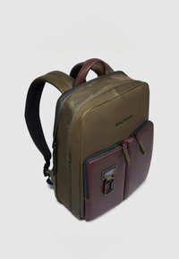 Zaino verde oliva e bordeaux con texture in pelle liscia, doppia cerniera frontale e spallacci imbottiti. Dotato di manico robusto sulla parte superiore.