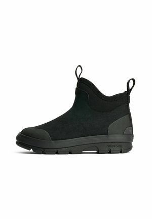 Sort ankelhøj slip-on sko med tyk gummisål, teksturerede tå- og hælkapsler samt stoftrækflige foran og bagpå.