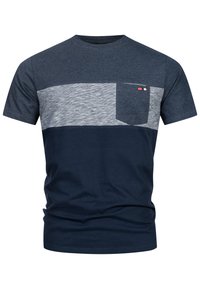 Camiseta bloqueada en color azul marino y gris claro, con mangas cortas, cuello redondo y un bolsillo en el pecho izquierdo que presenta un pequeño logo decorativo. Material de algodón.