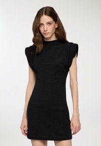 Czarna sukienka z krótkim rękawem i poduszonymi ramionami, wykonana z teksturowanej, lśniącej tkaniny. Dopasowany krój z wysokim dekoltem i długością powyżej kolan.