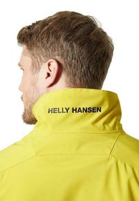 Giacca impermeabile gialla con colletto alto; presenta il logo nero "Helly Hansen" sulla schiena, texture liscia e design durevole.