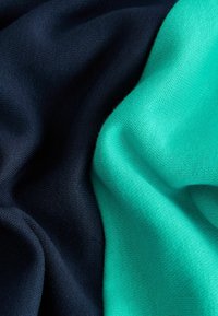 Bomuldsstof med mørk navy og livlige teal sektioner, med en blød, glat tekstur og en let glans.