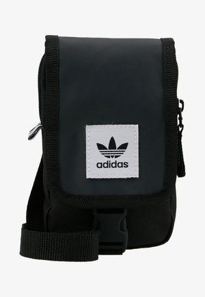 Bolso cruzado de nylon negro con un zipper frontal, correa ajustable y un parche de logo blanco bordado que presenta tres rayas negras.