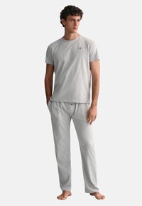 Gray short-sleeve t-shirt and matching pajama pants made of soft fabric. Shirt features a small logo; pants have an elastic waistband.