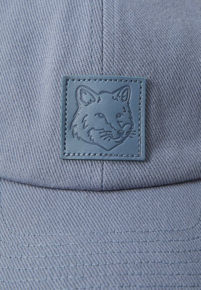 Casquette en coton bleu avec une finition texturée et un patch en cuir bleu carré arborant un motif de tête de renard en relief.