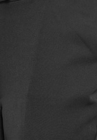 Svart tyg, jämn textur, något sträckt. Materialet är ogenomskinligt utan synliga mönster eller hårdvara.