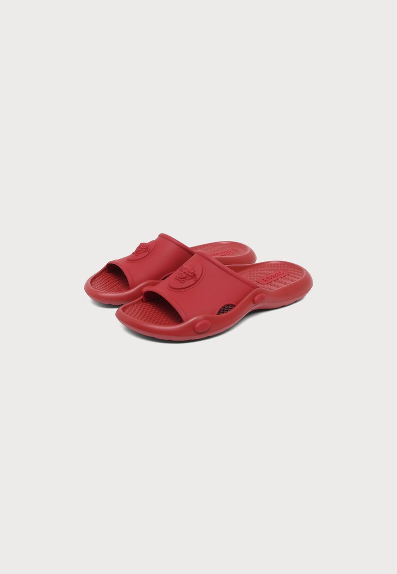 Paar rote Gummi-Slipper mit strukturiertem Fußbett und erhöhtem Logo auf dem breiten Frontriemen, vor einem schlichten weißen Hintergrund dargestellt.