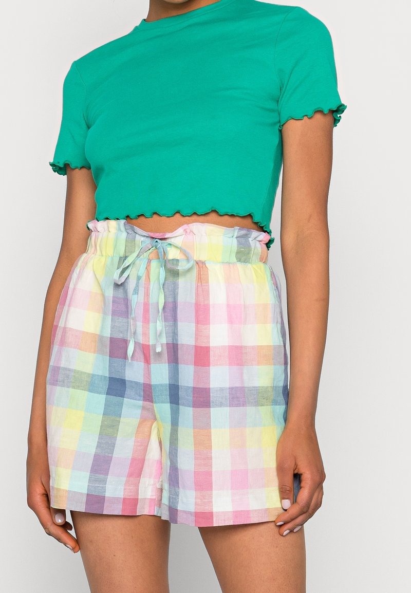 Zielona krótka koszulka z falistym wykończeniem połączona z wielokolorowymi pastelowymi szortami w kratę, z ściągaczem w pasie i luźnym krojem.