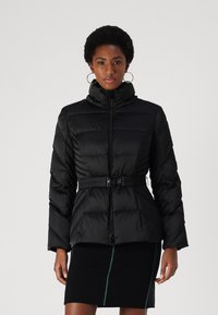 Giubbotto puffer nero con colletto alto, chiusura con zip e vita con cintura. Presenta un design trapuntato orizzontale e due tasche frontali.