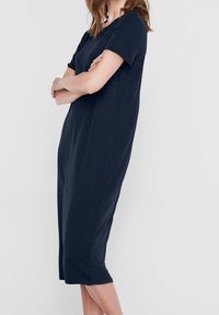 Mörkblå knälång klänning i mjukt tyg, med korta ärmar och en avslappnad passform, rund halsringning och inga synliga mönster.