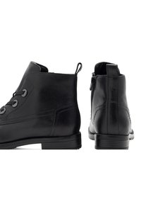 Černé kožené kotníkové boty s hladkým textilním povrchem, kulatou špičkou, zapínáním na tkaničky vpředu a detailem se zipem vzadu; plochý podpatek s minimálním vzorkem.