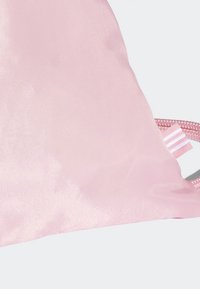 Rosa dragsko-påse i slät satin, med en texturerad yta och en randig etikett i pastellfärger på sidan.