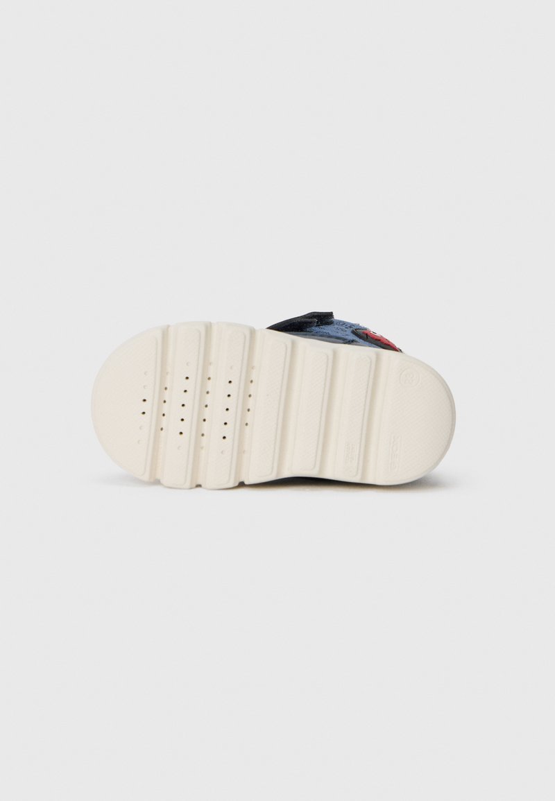 Podeszwa sneakersów o płaskiej, teksturowanej powierzchni w kolorze kremowym. Charakteryzuje się licznymi poziomymi bruzdami oraz małymi perforacjami zapewniającymi przyczepność.