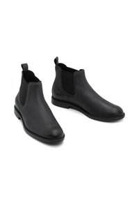 Melnas ādas Čelsijas zābaki ar elastīgām sānu daļām, noapaļota purngala un vilkšanas cilpiņām vieglai uzvilkšanai. Gluda tekstūra un minimālisma dizains.