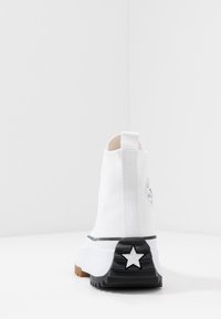 Białe ankle boots na płaskiej podeszwie z czarno-białą platformą, z akcentem w kształcie gwiazdy na obcasie oraz teksturowaną podeszwą z gumy.