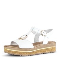 White leather sandals with a T-strap design, a gold circular accent, and a wedge sole featuring a textured wood pattern and rubber base.