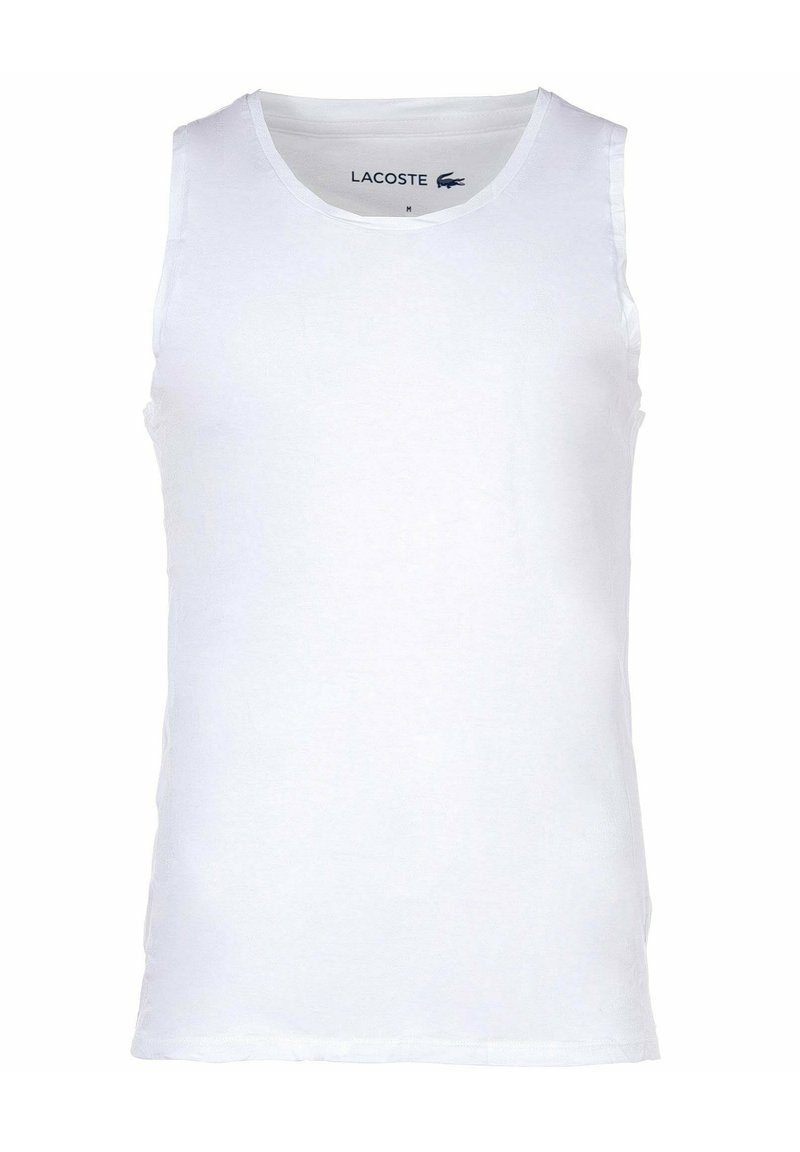 Canotta bianca realizzata in cotone morbido. Girocollo e senza maniche. Presenta un piccolo logo Lacoste vicino al colletto. Design semplice, senza motivi.