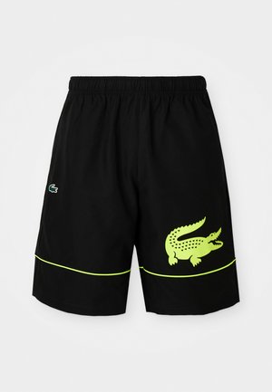 Shorts atletici negri cu talie elastică, logo cu crocodil neon galben pe piciorul drept, logo mai mic pe piciorul stâng și detaliu cu piping neon galben.