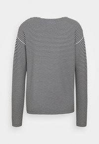 Haut à manches longues rayé noir et blanc avec un col rond, tissu doux et coupe décontractée. Aucune étiquette ou logo visible.