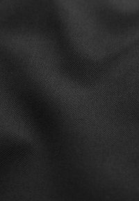 Tissu noir texturé avec un tissage lisse et un léger éclat, affichant de subtiles variations d'ombre et de lumière à la surface.