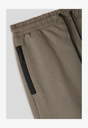 Khaki dresowe spodnie z wiązanym w pasie, elastycznym mankietem i boczną kieszenią na zamek błyskawiczny, z czarnymi akcesoriami zapewniającymi bezpieczne przechowywanie.