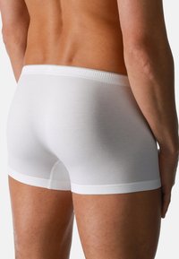 Boxer shorts bianchi in cotone con una vestibilità aderente, caratterizzati da una texture liscia e un semplice elastico in vita. Dettagli delle cuciture visibili lungo le cuciture.