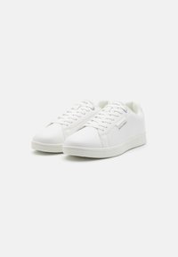 Vita sneakers med slät läderöverdel, rund tå, platt gummisula och snörningsdesign. Har logotyp på sidan och minimalistiska detaljer.