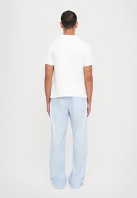 White cotton T-shirt and light blue striped pajama pants with a loose fit, featuring a straight leg and subtle cuffs at the bottom.