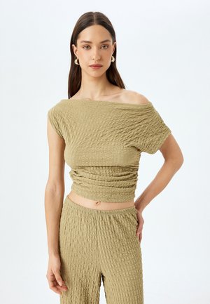 Olijfgroene twee-delige set gemaakt van gestructureerde, gekreukte stof. De top heeft een off-shoulder ontwerp en de onderkant heeft een elastische tailleband.