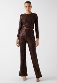 Completo due pezzi color marrone con paillettes, composto da un top corto a maniche lunghe e pantaloni svasati, caratterizzato da una vita aderente e una texture liscia.