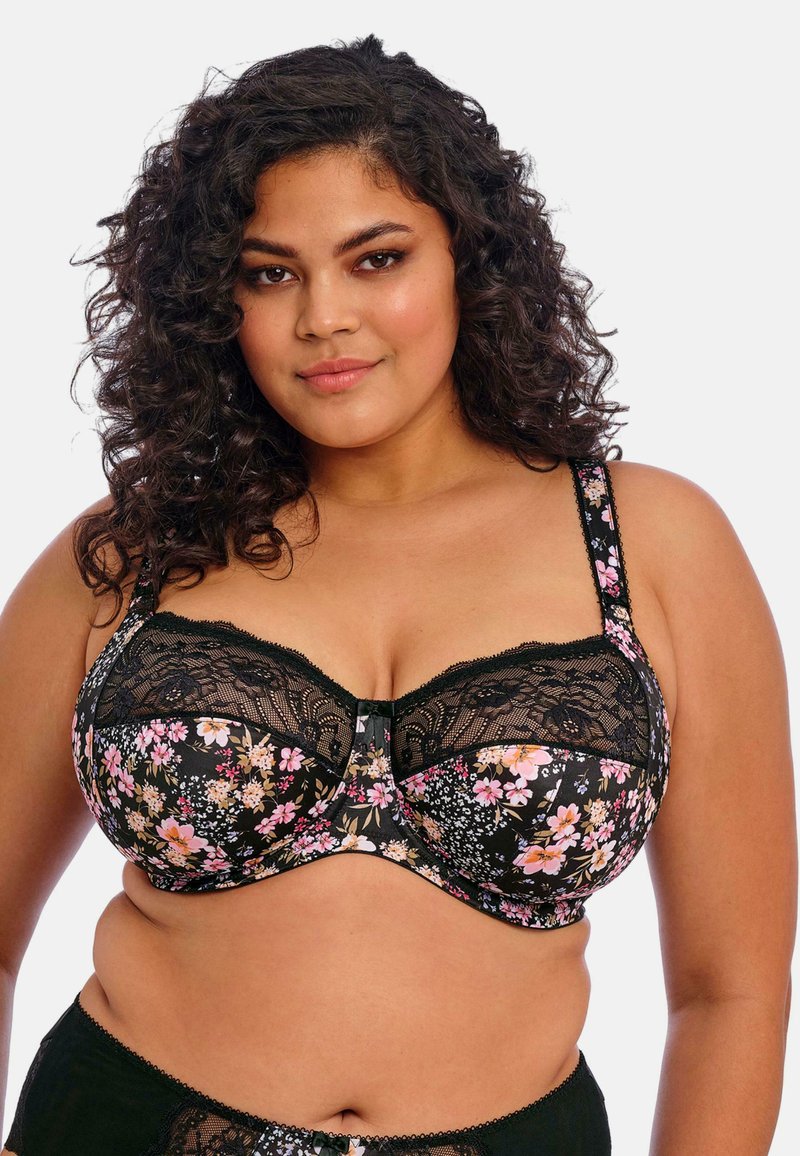 Sujetador negro con estampado floral y detalles de encaje, que presenta flores rosas y blancas, acentos de encaje y un cierre frontal. Incluye tirantes ajustables.